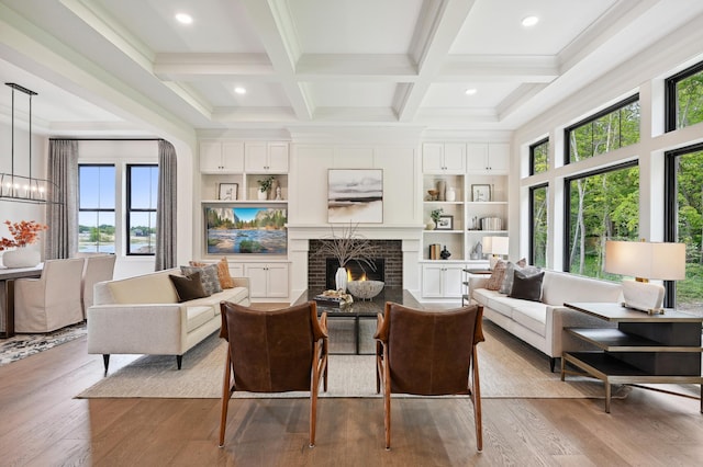 living room featuring beamed ceiling, coffered ceiling, light wood-type flooring, and a fireplace