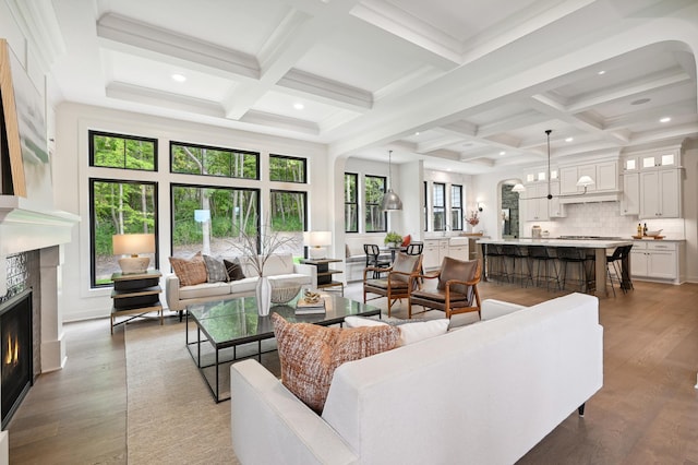 living room with beamed ceiling, coffered ceiling, a fireplace, and dark hardwood / wood-style flooring