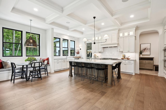 kitchen featuring hanging light fixtures, white cabinets, and light hardwood / wood-style flooring