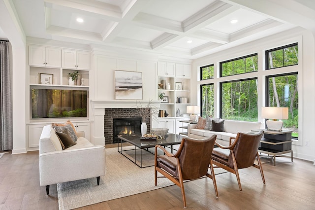 living room with a brick fireplace, a wealth of natural light, beam ceiling, and light hardwood / wood-style flooring