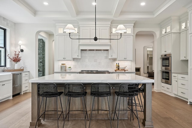 kitchen with appliances with stainless steel finishes, decorative light fixtures, white cabinets, and a spacious island