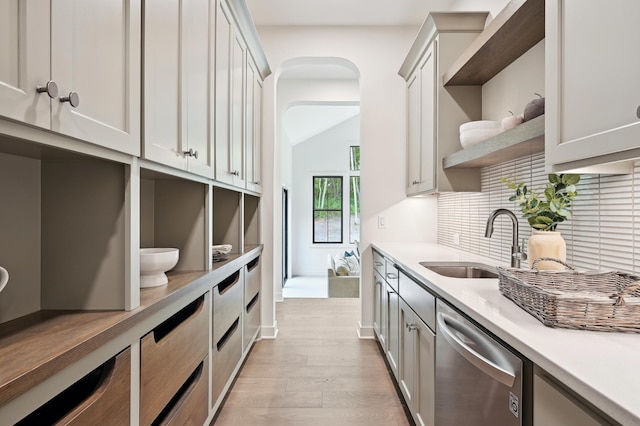 kitchen with tasteful backsplash, dishwasher, white cabinetry, sink, and light wood-type flooring