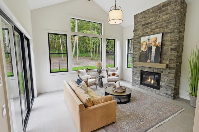 living room featuring a stone fireplace, a wealth of natural light, high vaulted ceiling, and light tile patterned flooring