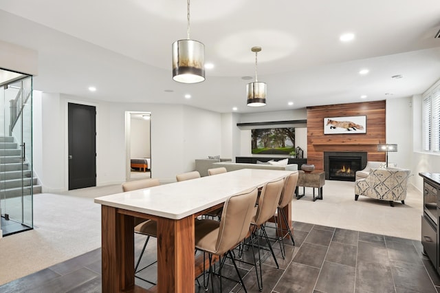 dining room featuring a large fireplace and dark carpet