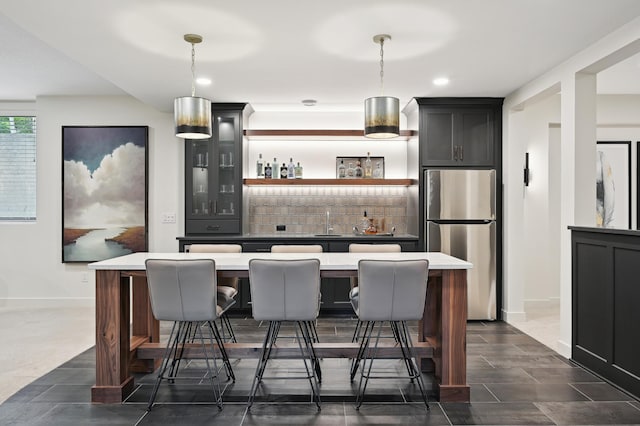 bar featuring sink, stainless steel fridge, backsplash, and decorative light fixtures