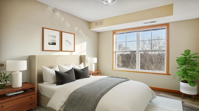 bedroom with baseboards, visible vents, and wood finished floors