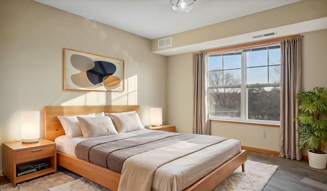 bedroom with visible vents, baseboards, and wood finished floors