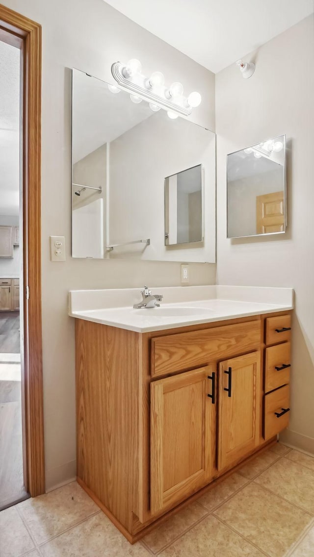 bathroom with tile patterned flooring, baseboards, and vanity