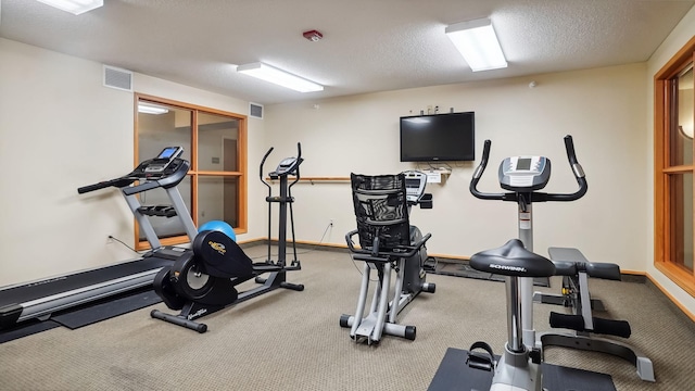 workout area with visible vents, a textured ceiling, and baseboards