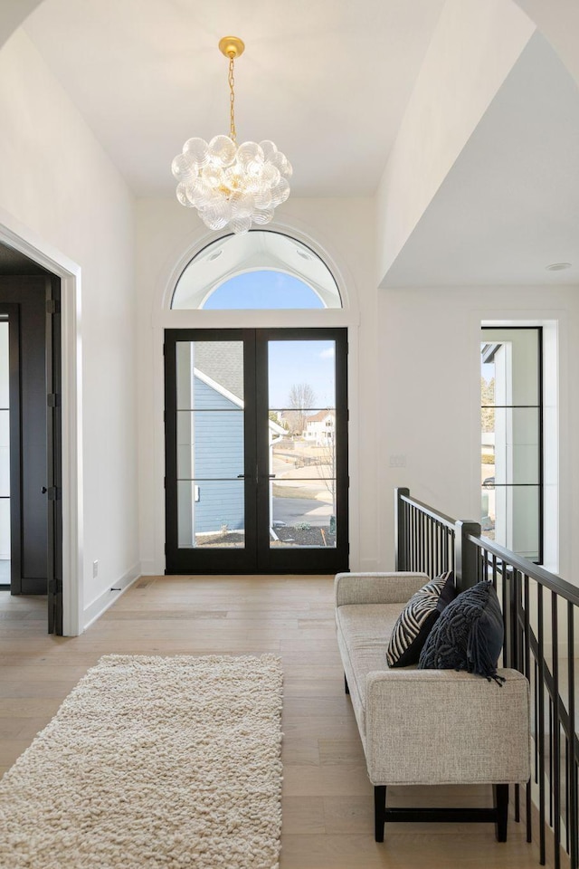 entryway featuring a notable chandelier, french doors, baseboards, and light wood-style floors