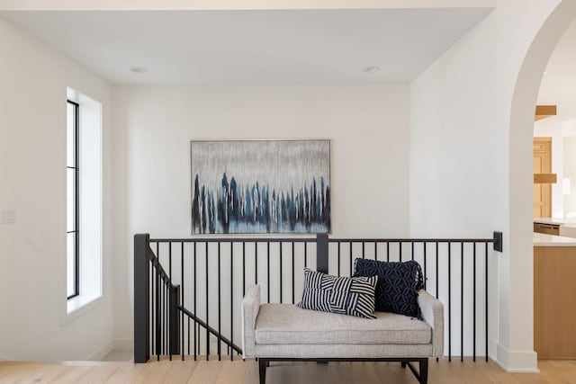 living area featuring arched walkways, an upstairs landing, baseboards, and wood finished floors