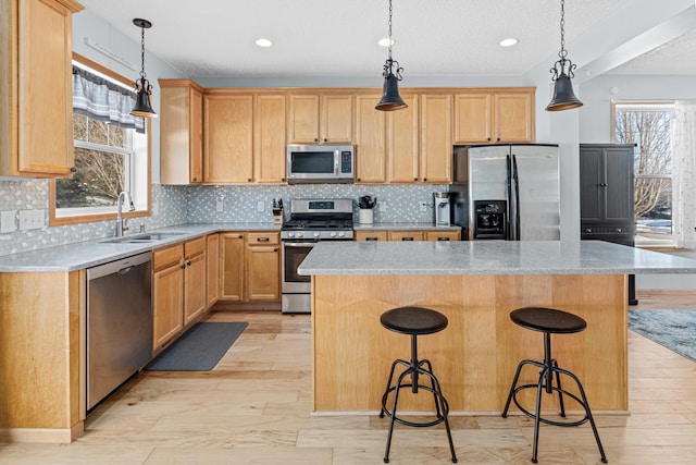 kitchen featuring sink, appliances with stainless steel finishes, a breakfast bar area, and a center island