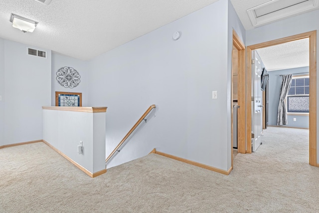 corridor featuring a textured ceiling and light colored carpet