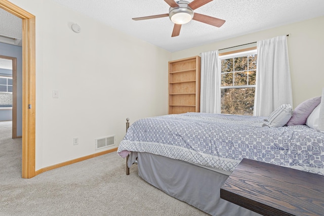 bedroom with ceiling fan, carpet floors, and a textured ceiling