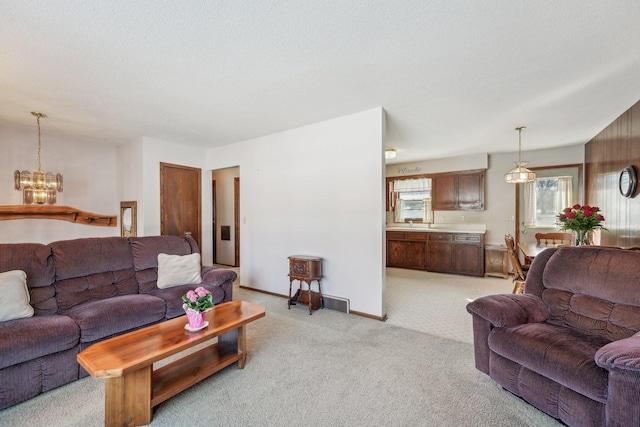 living room featuring baseboards, a textured ceiling, a chandelier, and light colored carpet