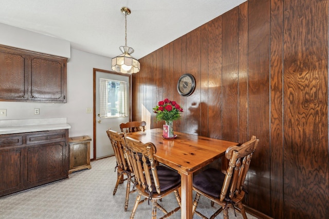 dining area featuring light carpet and wooden walls