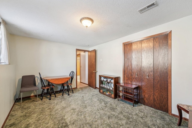 dining space with carpet, visible vents, a textured ceiling, and baseboards