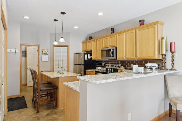 kitchen with a breakfast bar, decorative light fixtures, appliances with stainless steel finishes, kitchen peninsula, and backsplash