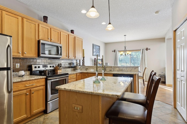 kitchen featuring a kitchen island, decorative light fixtures, tasteful backsplash, a breakfast bar area, and stainless steel appliances