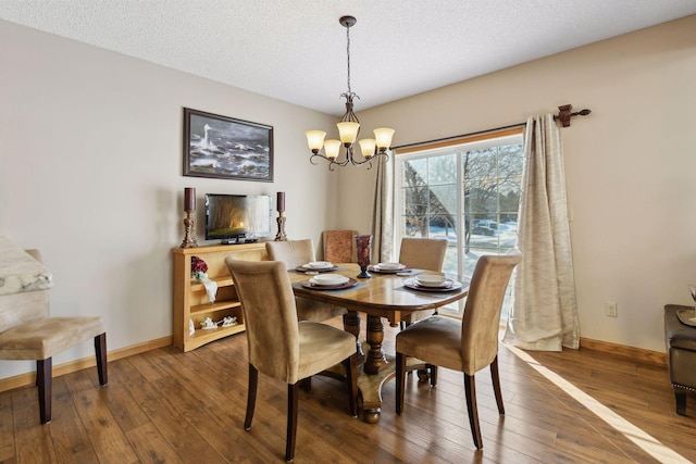 dining area featuring dark hardwood / wood-style floors, a textured ceiling, and an inviting chandelier