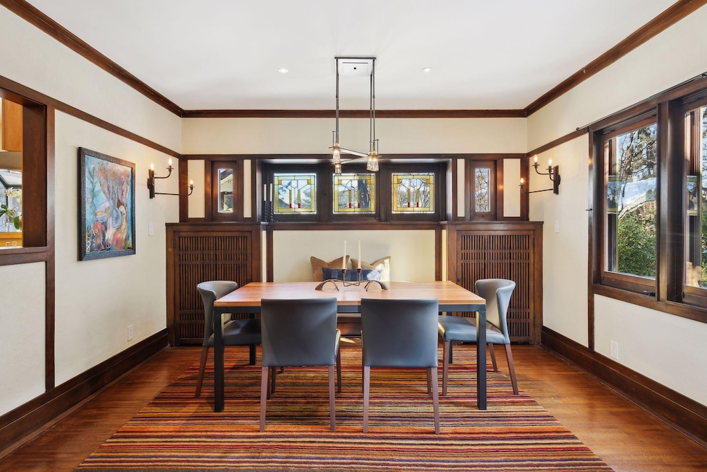 dining space with dark wood-type flooring and crown molding