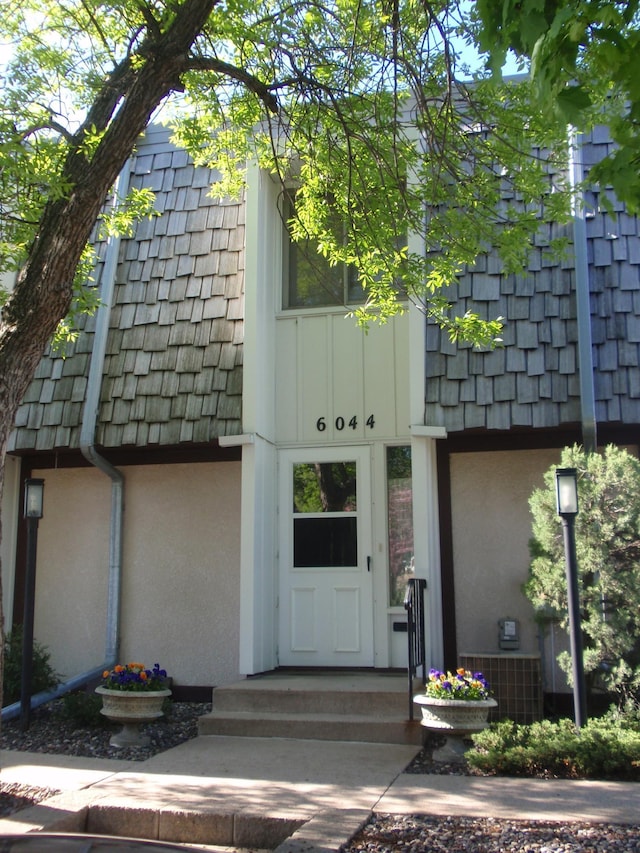 entrance to property with mansard roof and stucco siding