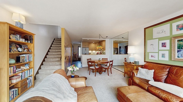 living area featuring stairway and light colored carpet