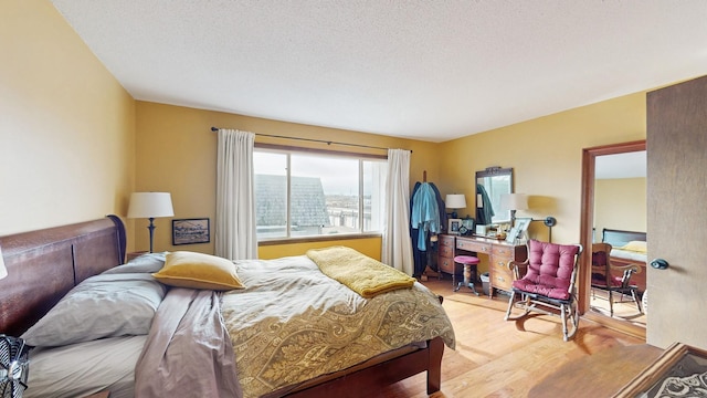 bedroom featuring light wood-type flooring, a city view, and a textured ceiling