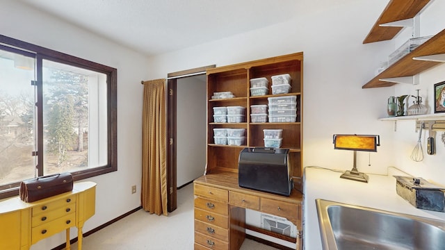 office with light carpet, plenty of natural light, baseboards, and a sink