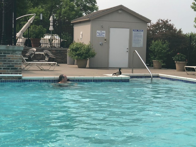 pool featuring a patio, an outdoor structure, and fence