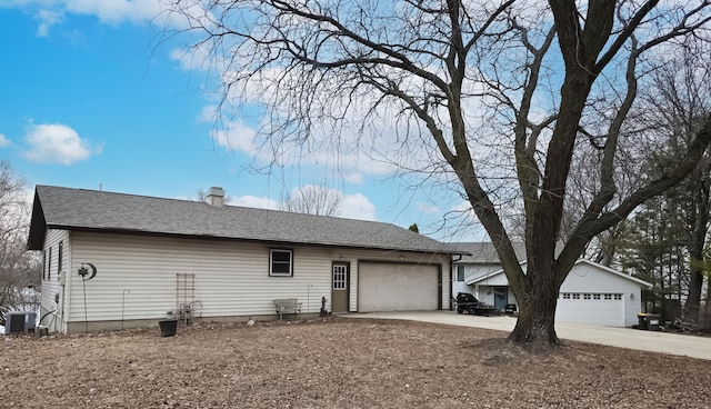 view of property exterior featuring an attached garage, central AC, and roof with shingles