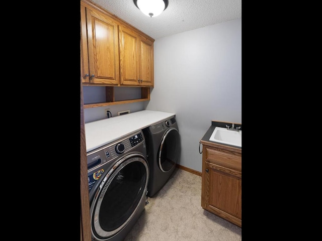 clothes washing area featuring sink, cabinets, washer and dryer, a textured ceiling, and light carpet