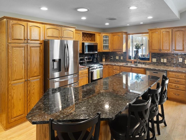 kitchen with appliances with stainless steel finishes, a breakfast bar, sink, a center island, and light hardwood / wood-style floors