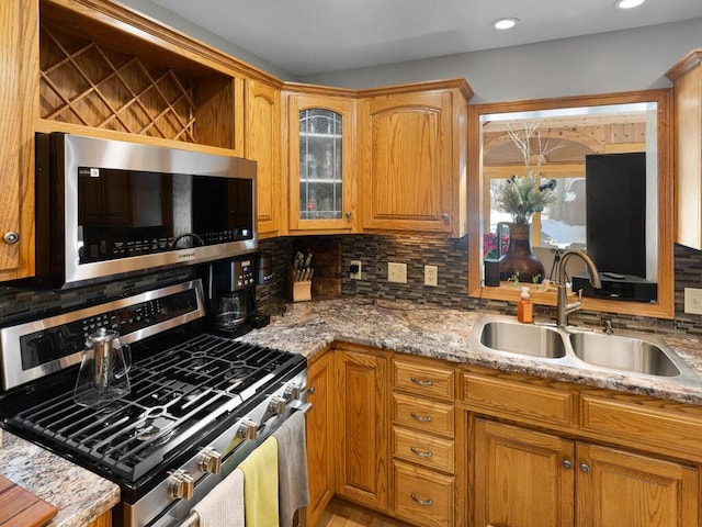 kitchen featuring light stone counters, appliances with stainless steel finishes, sink, and backsplash