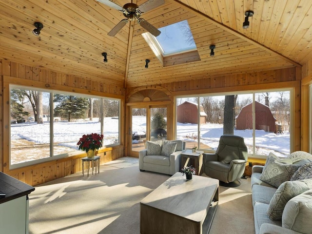 living room with ceiling fan, a skylight, light carpet, wooden ceiling, and wood walls