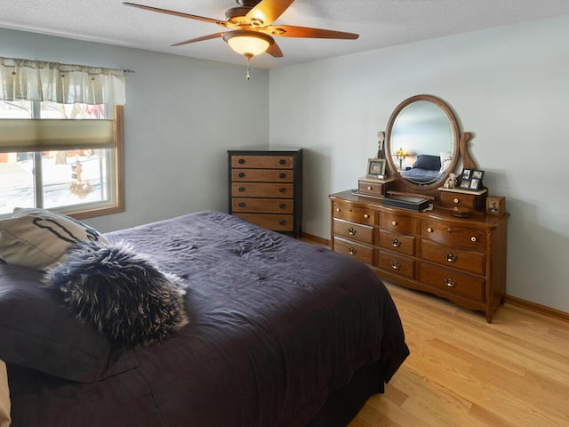 bedroom featuring ceiling fan, a textured ceiling, and light wood-type flooring