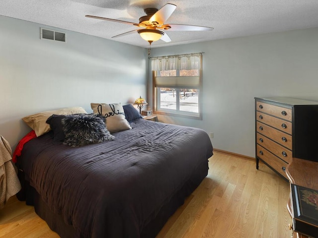 bedroom featuring ceiling fan, a textured ceiling, and light hardwood / wood-style flooring