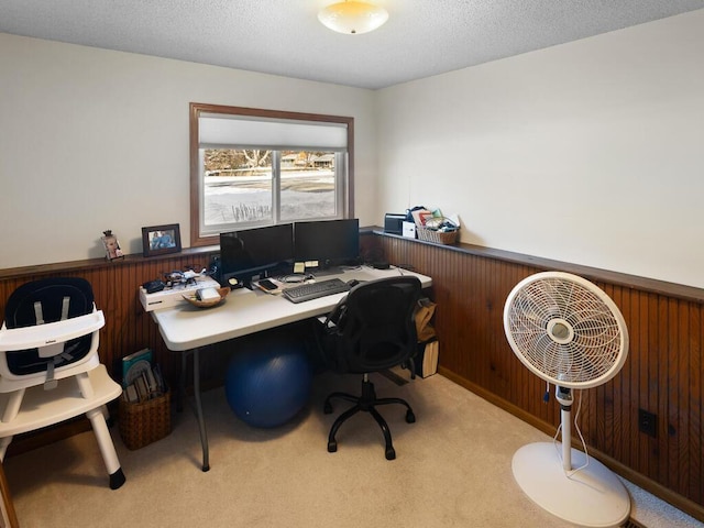 carpeted office with a textured ceiling and wood walls