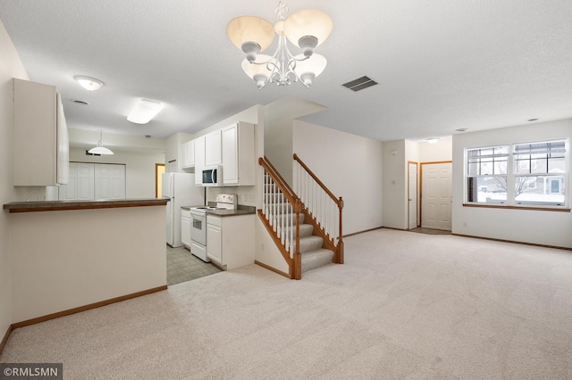 unfurnished living room with light carpet, a notable chandelier, and a textured ceiling