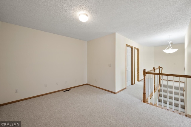 carpeted empty room featuring a textured ceiling