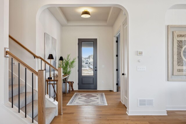 4718 Ordell Trl N, Stillwater, MN 55082 - entryway with light wood-type flooring, a raised ceiling, arched walkways, baseboards, and stairway