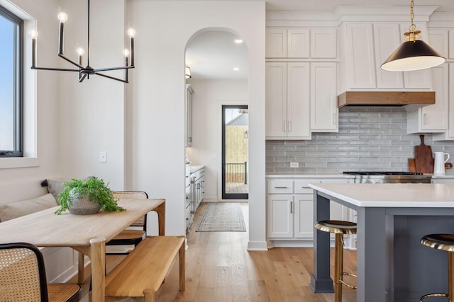 4718 Ordell Trl N, Stillwater, MN 55082 - kitchen with light countertops, light wood-style flooring, decorative backsplash, white cabinetry, and arched walkways