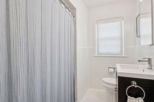 full bath with wainscoting, toilet, tile walls, and vanity