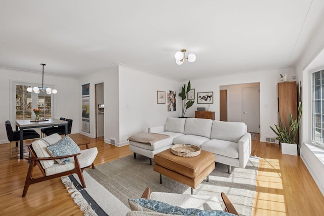 living area featuring a notable chandelier, visible vents, a healthy amount of sunlight, and light wood-style floors