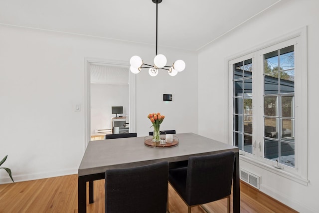 dining room featuring visible vents, baseboards, an inviting chandelier, and wood finished floors