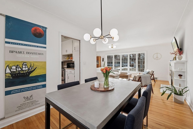 dining room featuring baseboards, an inviting chandelier, and light wood finished floors