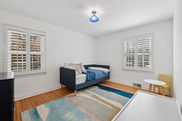 bedroom featuring visible vents, baseboards, and wood finished floors