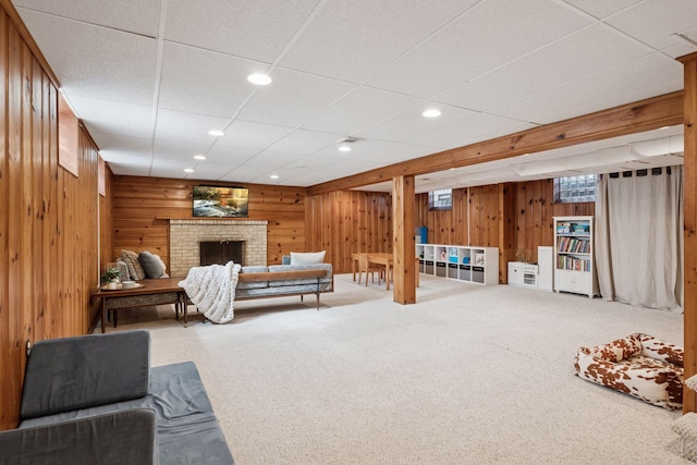 living area featuring recessed lighting, carpet floors, wooden walls, a fireplace, and a paneled ceiling