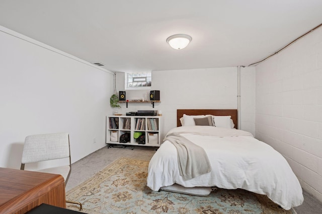 bedroom featuring visible vents, carpet flooring, and concrete block wall