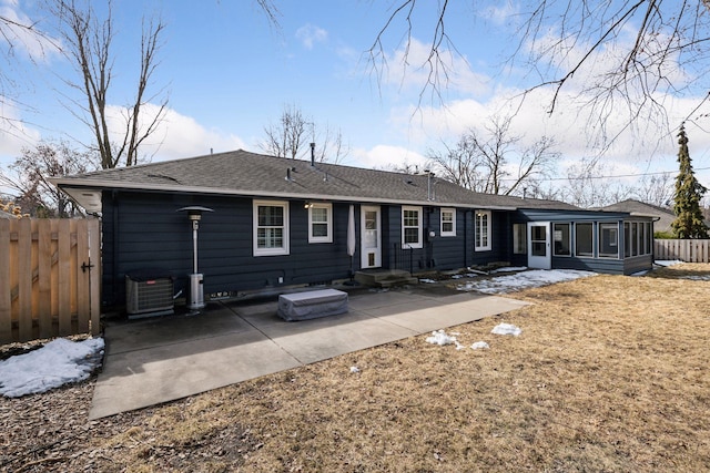 view of front facade featuring a patio, central AC, fence, roof with shingles, and a sunroom